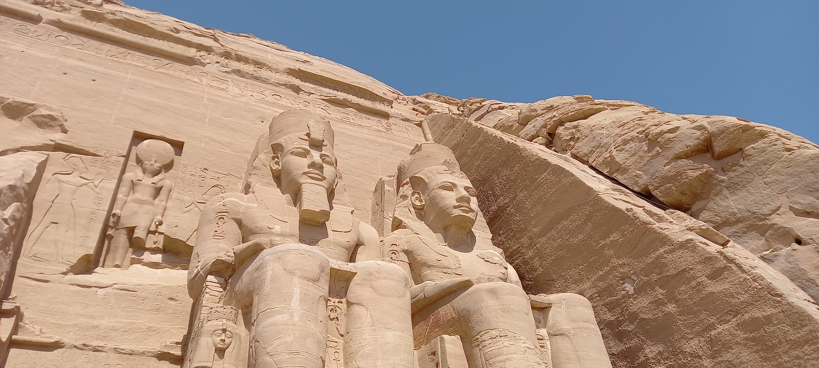 Gros plan de grandes statues de pierre sculptées dans une paroi rocheuse.