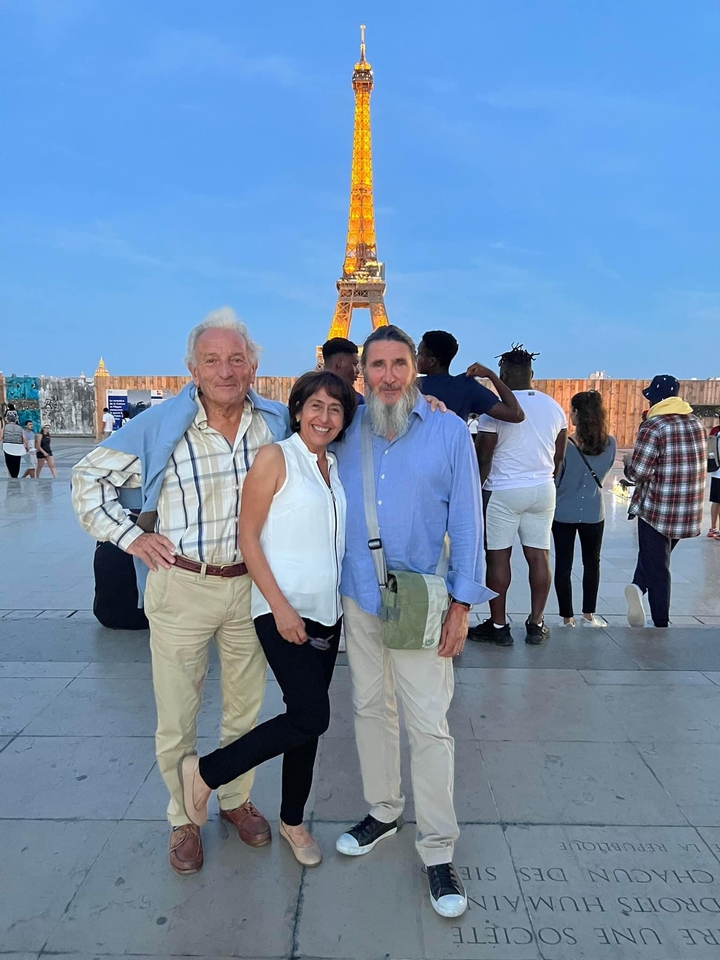 Trois personnes posent devant un monument célèbre avec une tour en arrière-plan.