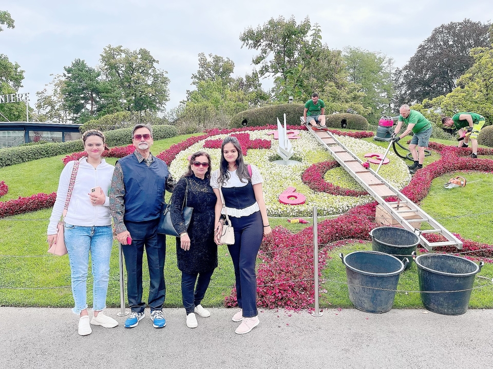 Groupe de personnes posant devant une horloge florale.