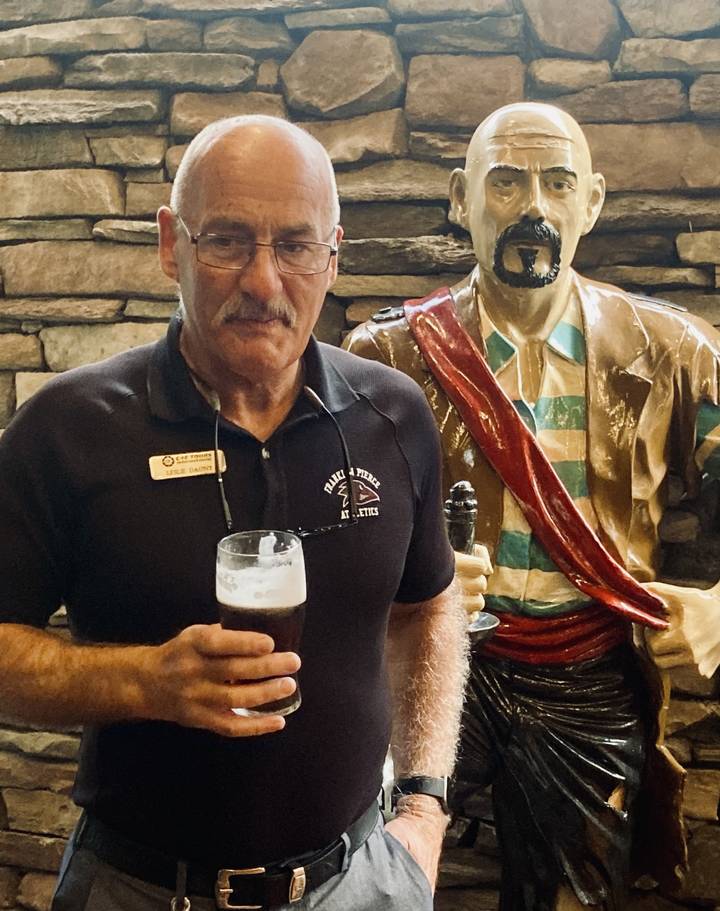 Personne tenant une pinte de bière à l'intérieur d'un pub.