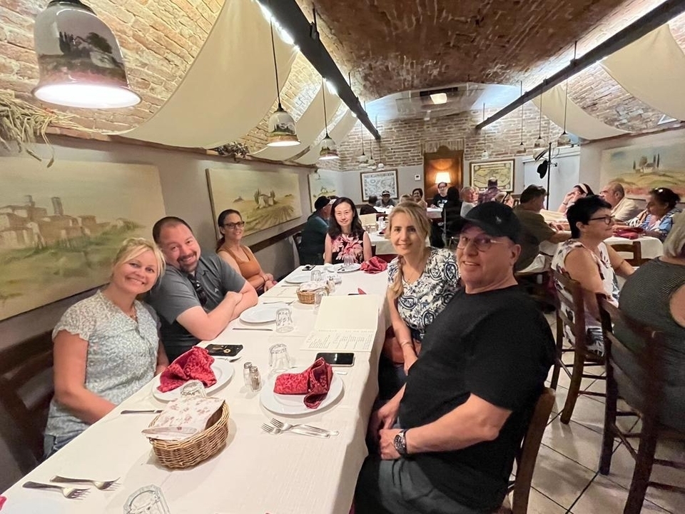 Groupe de personnes dînant dans un restaurant avec des arcs en brique et des peintures sur le mur.
