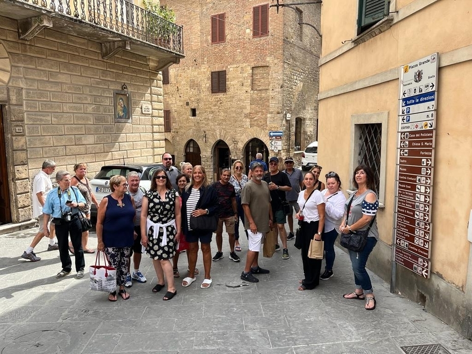 Groupe de touristes posant dans une rue avec des bâtiments historiques.