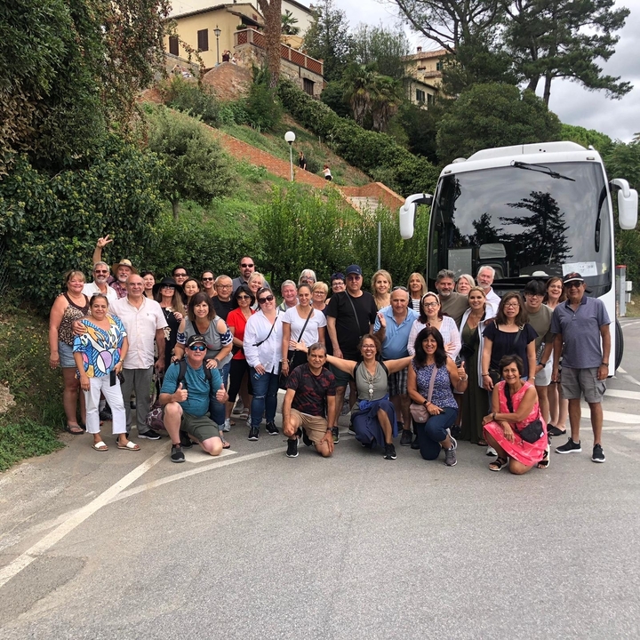 Groupe de touristes posant devant un autocar blanc.