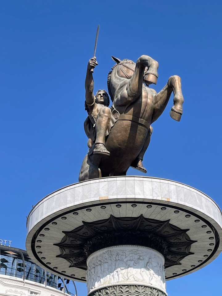 Statue d'une figure sur un cheval sur un piédestal avec un ciel bleu.