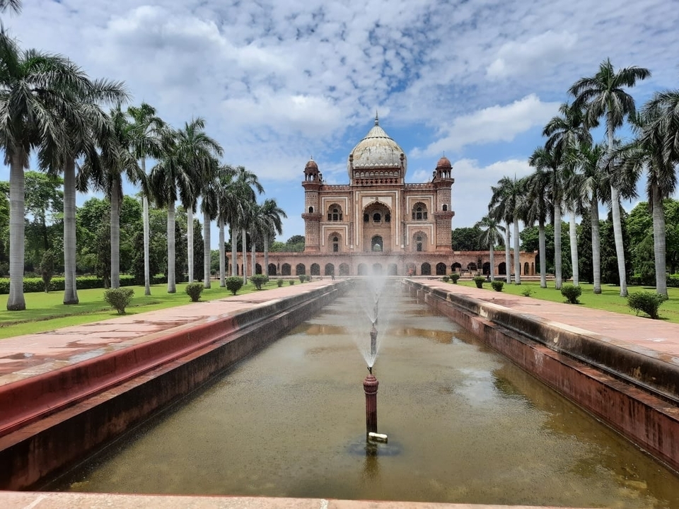 Fontaine et tombeau dans un jardin entouré de palmiers.