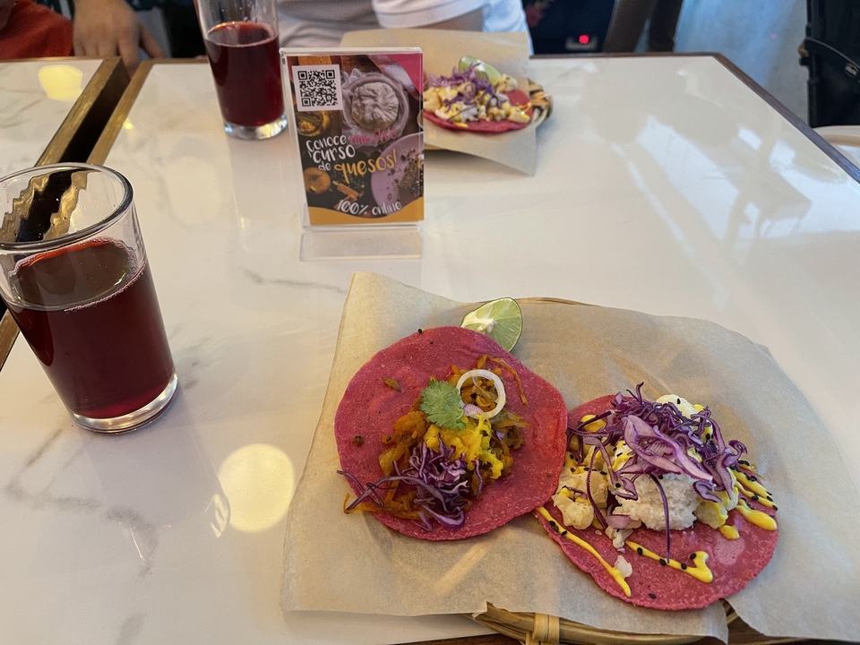 Gros plan de tacos mexicains traditionnels sur une table avec un verre de boisson.