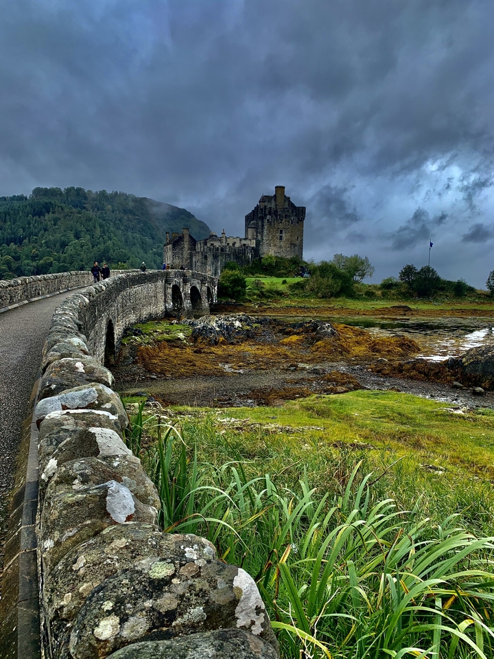 Iconic medieval castle with a stone bridge over a scenic landscape.