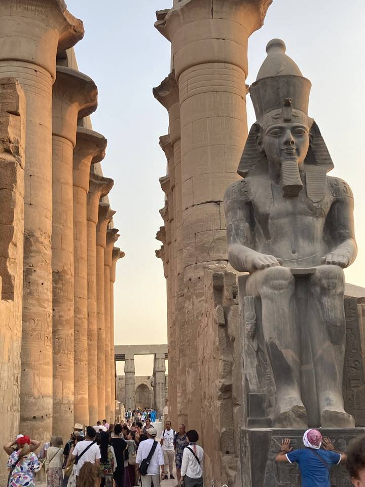 Grandes statues et colonnes antiques avec des personnes qui marchent à proximité.