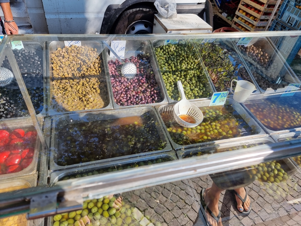 Variété d'olives et de cornichons exposée dans un étal de marché alimentaire.