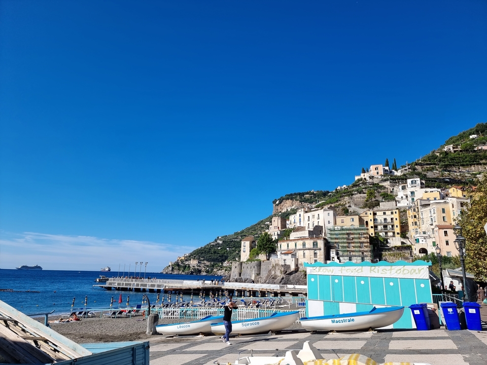Ville côtière avec des bâtiments colorés sur une colline surplombant la mer.