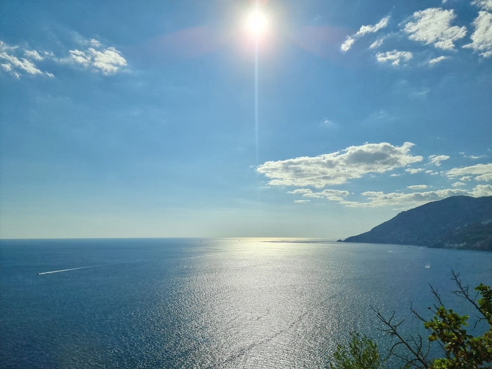 Vue océanique étendue avec le soleil qui brille intensément dans un ciel dégagé.