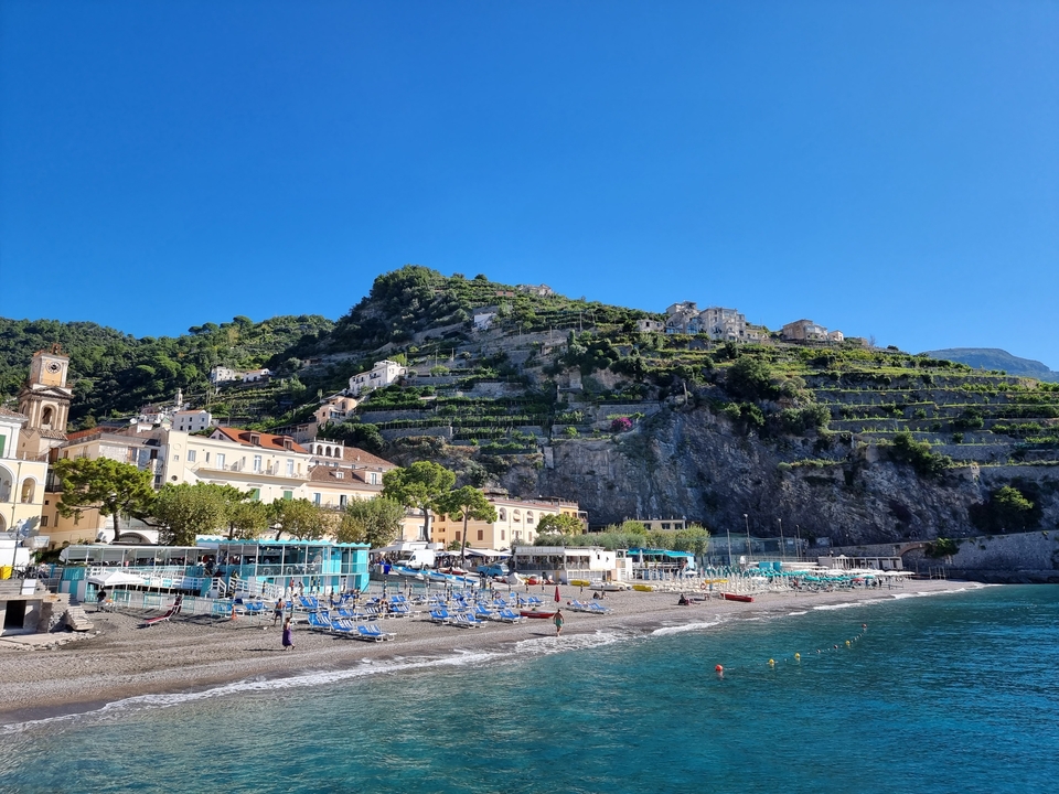 Paysage urbain côtier avec des parasols de plage colorés et des eaux océaniques sereines.