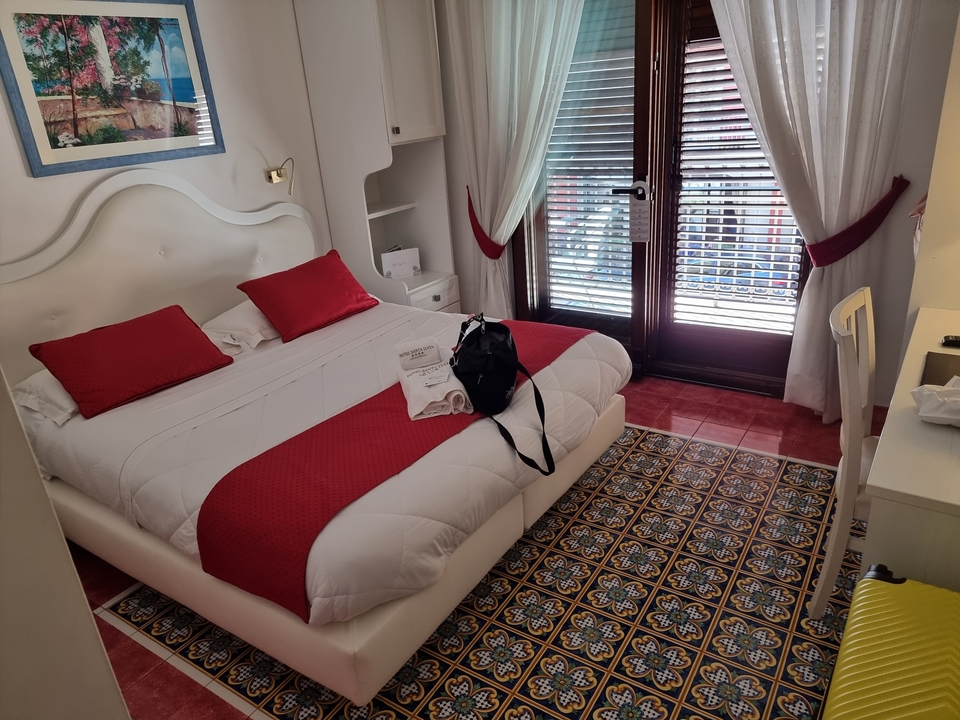Chambre d'hôtel bien décorée avec des accents rouges et un balcon.