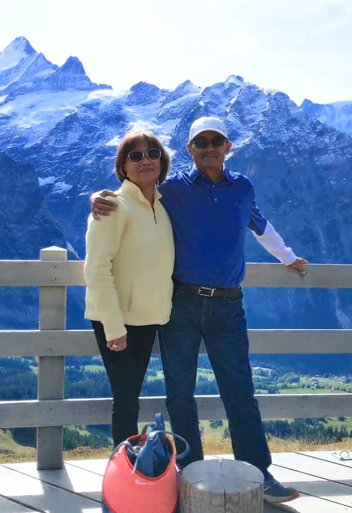 Couple posant devant un terrain montagneux enneigé.