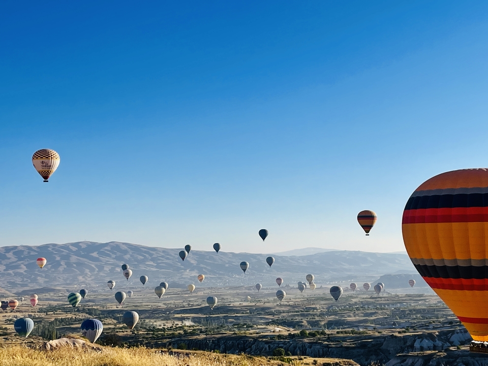 Plusieurs montgolfières dans le ciel au-dessus d'une vallée.