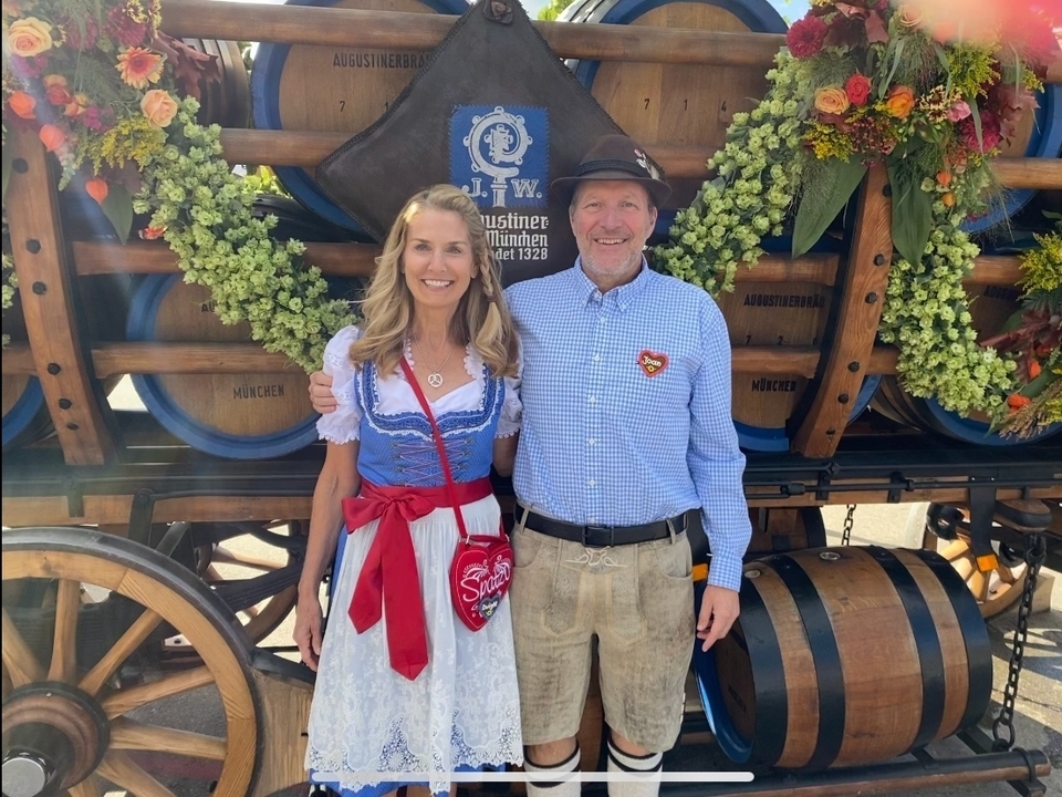 Un couple en tenue traditionnelle posant devant des tonneaux de bière.