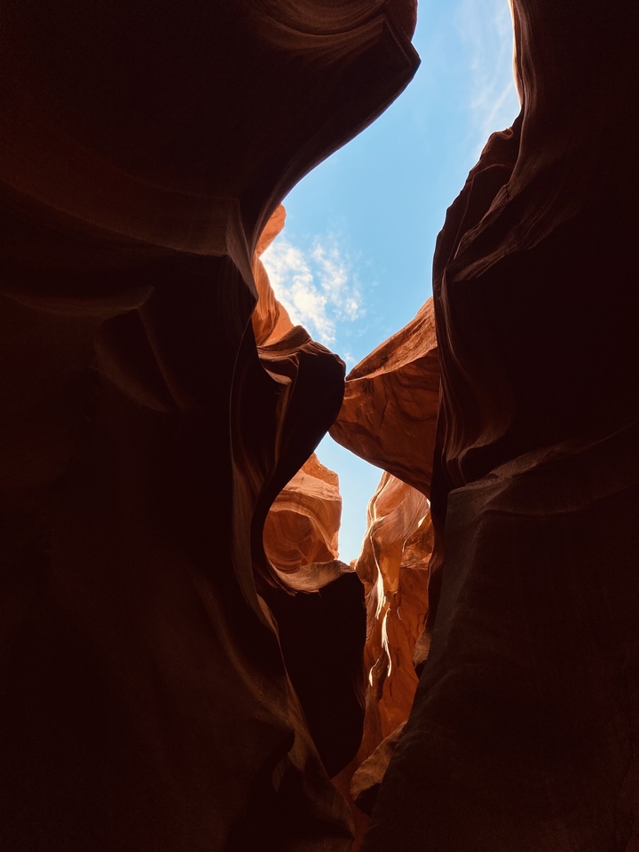 View from within a narrow sandstone canyon with blue sky above.