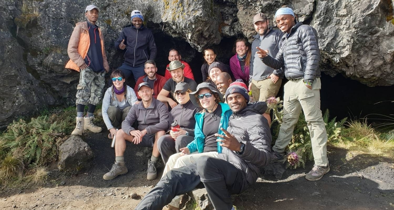 Groupe de randonneurs posant devant une paroi rocheuse.