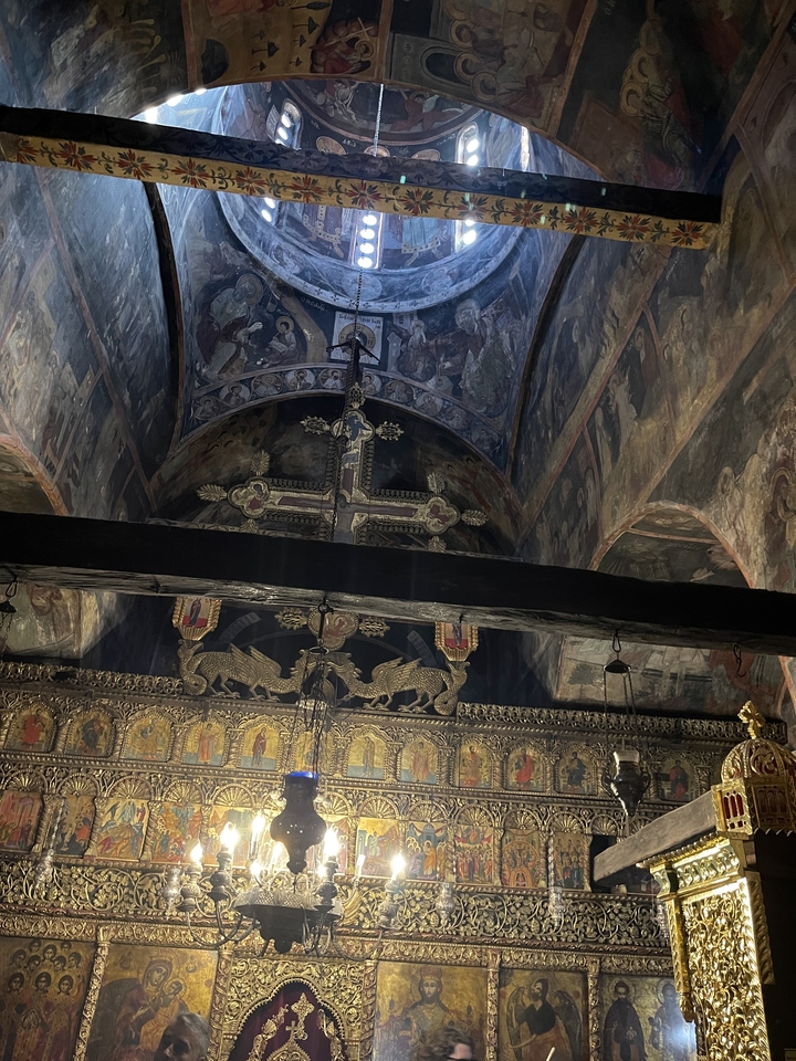 Intérieur d'une église avec des plafonds ornés de fresques et des poutres en bois.