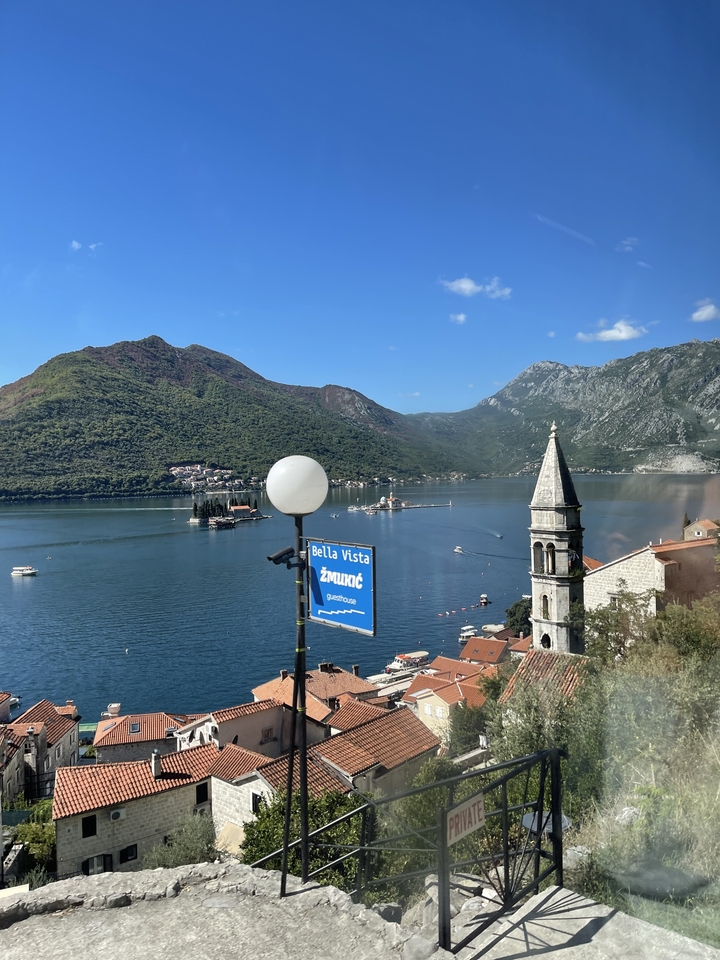 Une vue côtière pittoresque avec un clocher et un décor de montagne en arrière-plan.
