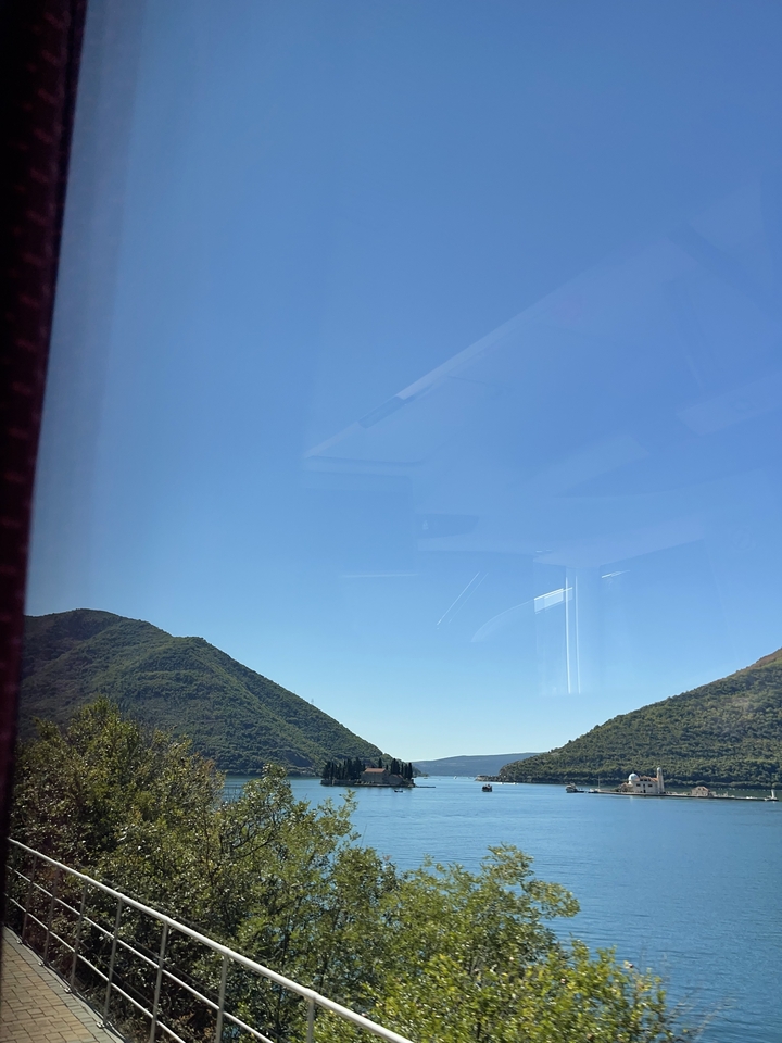 Une vue à travers une fenêtre reflétant l'intérieur du bus avec une montagne à l'extérieur.