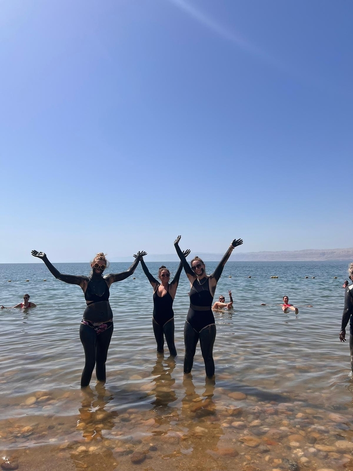 Des gens couverts de boue se tenant dans la mer Morte.