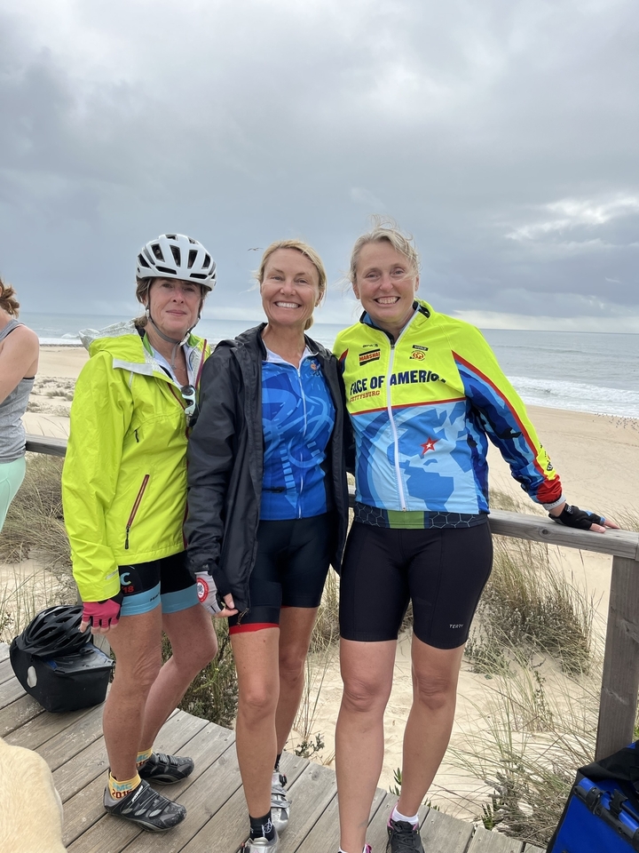 Trois cyclistes posant près d'une plage.