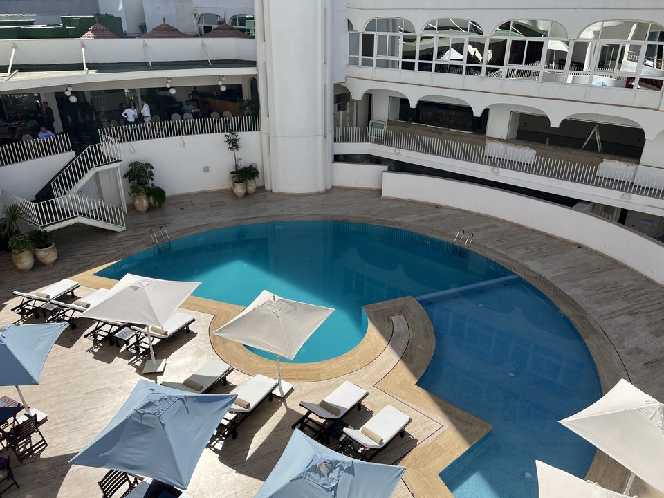Zone de piscine d'hôtel avec parasols et chaises longues.