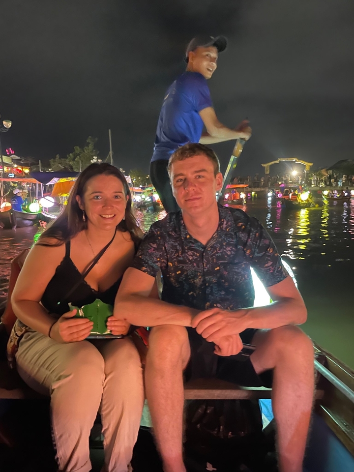 Couple assis au bord d'un canal avec des lumières colorées la nuit.