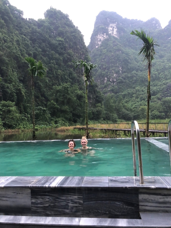 Deux personnes qui nagent dans une piscine avec un paysage de montagne en arrière-plan.
