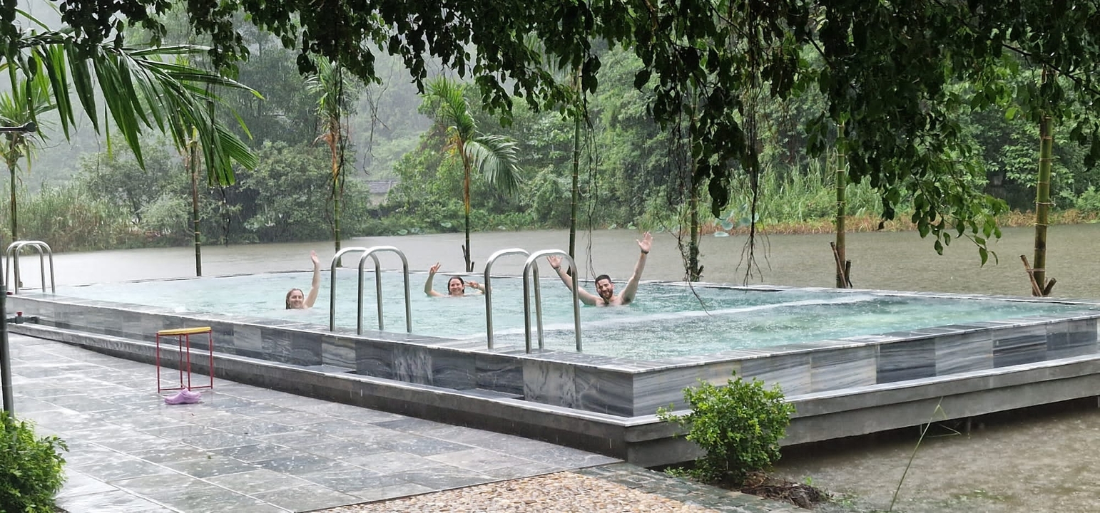 Groupe de personnes profitant d'une piscine extérieure entourée d'une végétation luxuriante.
