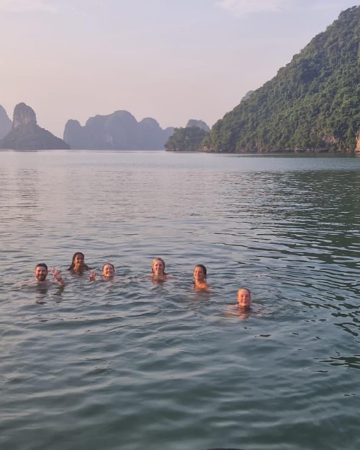 Groupe de personnes profitant d'une baignade avec des falaises rocheuses pittoresques et des eaux calmes.