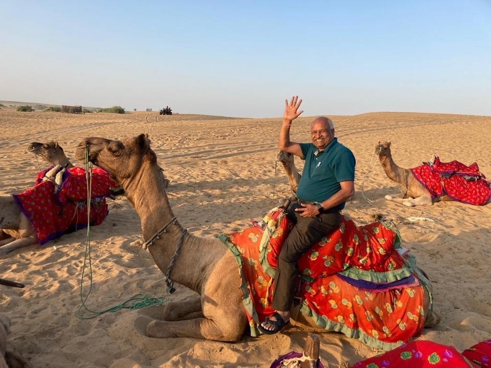 Homme montant un chameau orné de couvertures colorées dans le désert.