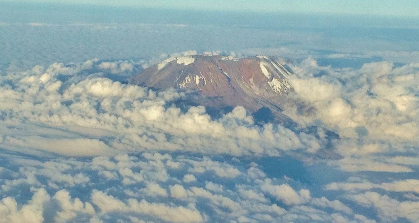 Vue aérienne d'un sommet de montagne enneigé entouré de nuages.