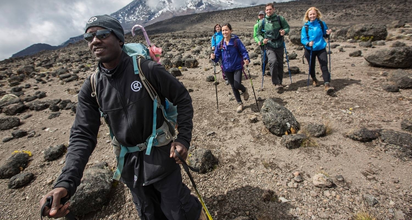 Groupe de randonneurs marchant à travers une zone montagneuse rocheuse.