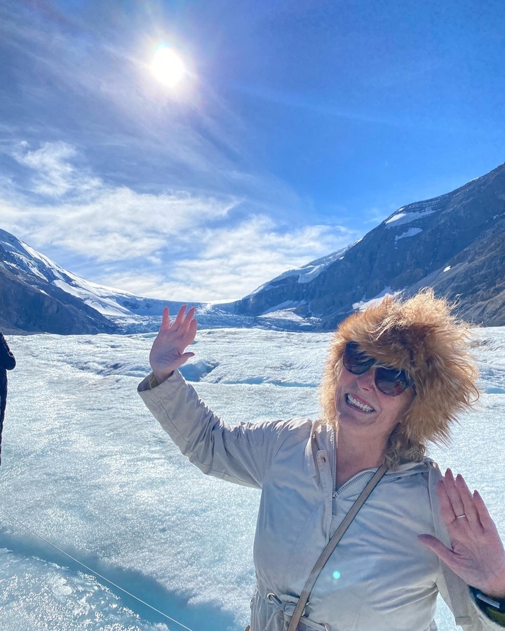 Femme en vêtements d'hiver souriante devant un glacier.