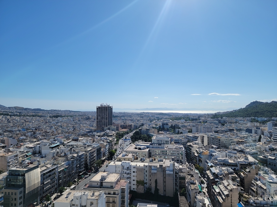 Vue panoramique d'un paysage urbain vu d'en haut, avec la mer au loin.