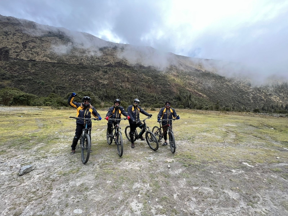 Groupe de quatre cyclistes posant sur un champ d'herbe.