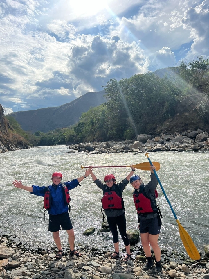 Trois personnes en équipement de rafting près d'une rivière.