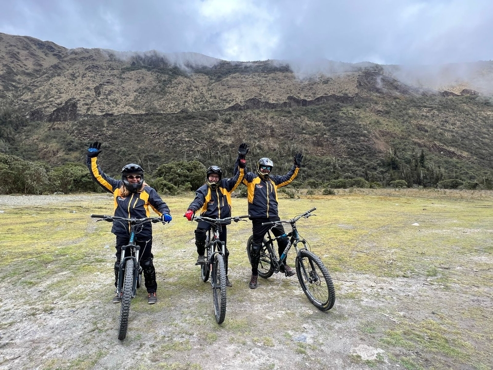 Trois cyclistes avec des casques les mains levées.