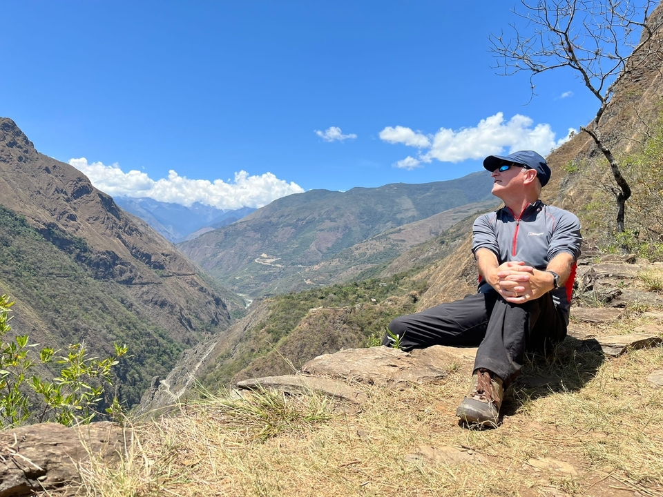 Personne assise sur le bord d'une falaise surplombant une vallée.