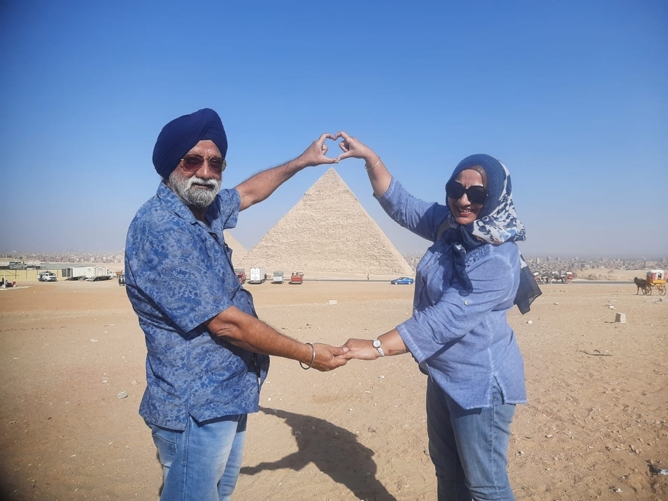 Des personnes posant avec leurs mains formant un cœur devant une pyramide.