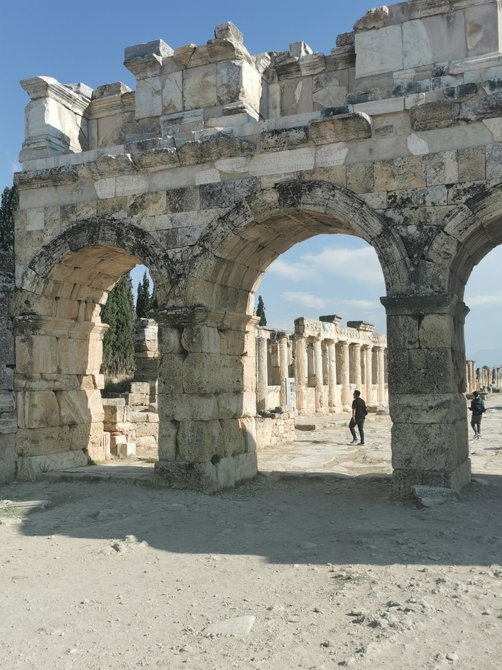 Des gens marchant à travers des arches de pierre historiques.