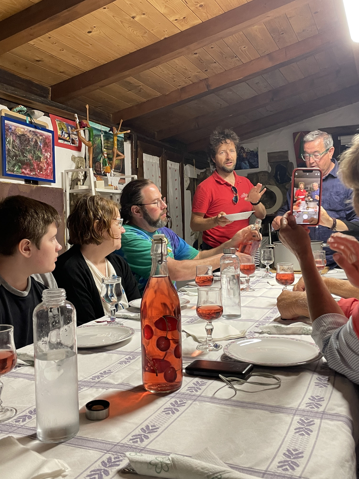 Groupe de personnes dînant à une table avec des boissons et de la nourriture.