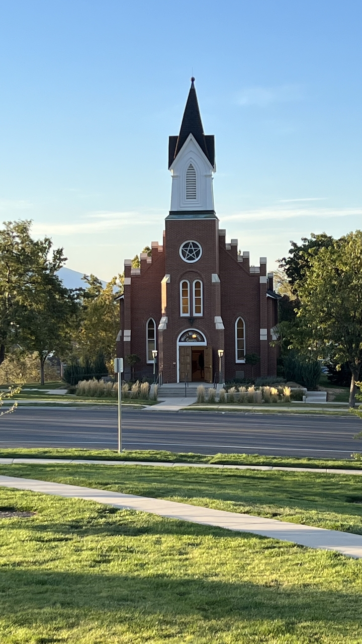Une église en brique avec un clocher et des terrains bien entretenus.