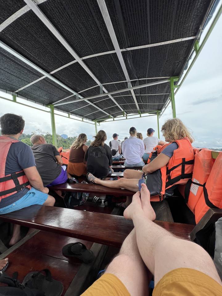 Groupe de personnes sur un bateau avec des gilets de sauvetage orange.