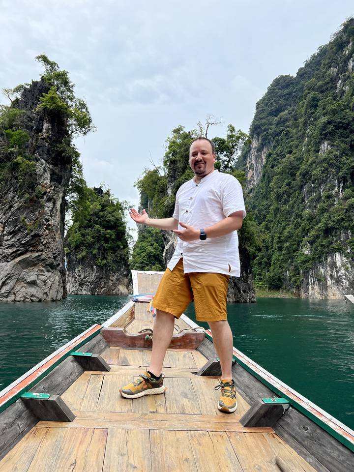 Person standing on a boat surrounded by scenic cliffs and water.