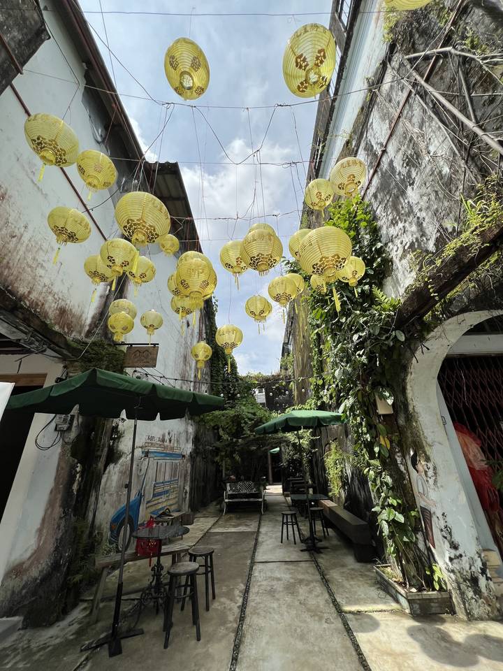 Decorated alley with hanging yellow lanterns.