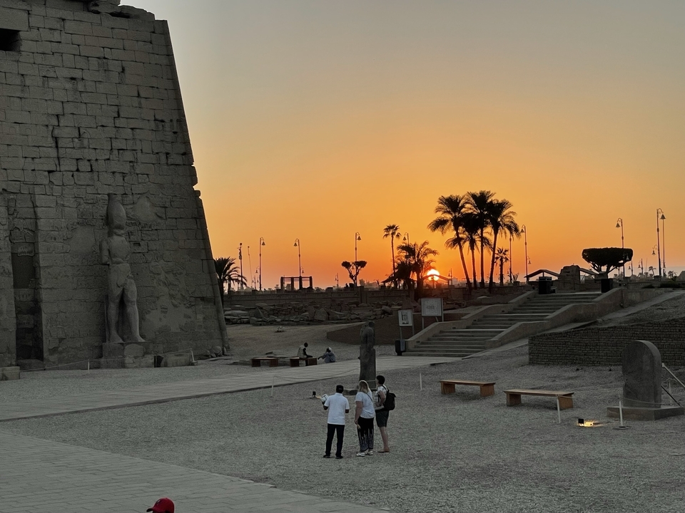 Sunset view with ancient temple and palm trees.