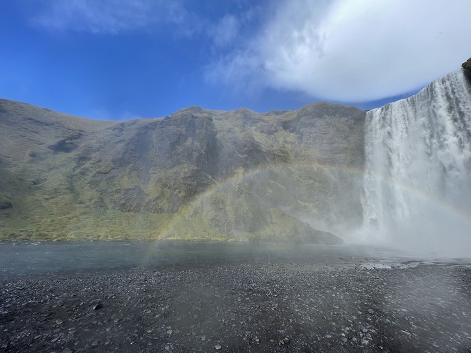 Waterfall with a visible rainbow and visitors nearby.